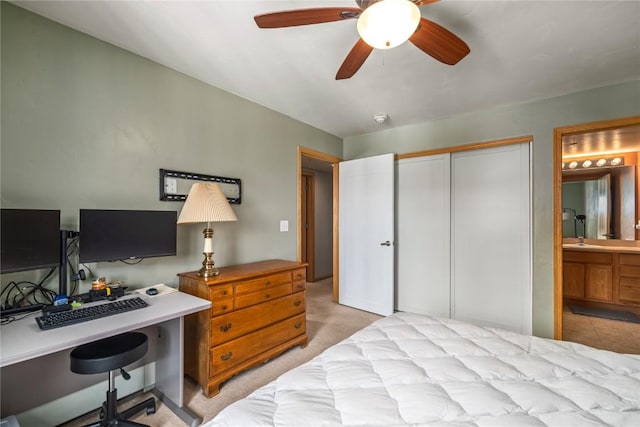 bedroom featuring a ceiling fan, ensuite bath, a sink, a closet, and light carpet