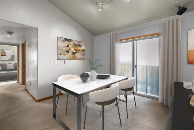 dining area featuring baseboards, light colored carpet, and vaulted ceiling