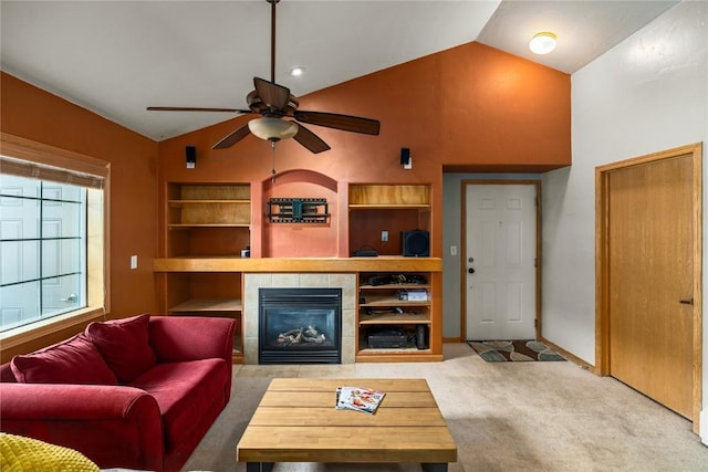 living area featuring carpet, built in features, lofted ceiling, a fireplace, and a ceiling fan