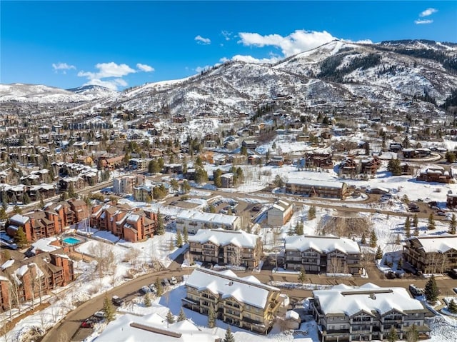 snowy aerial view featuring a mountain view and a residential view