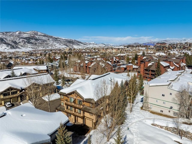 snowy aerial view with a mountain view and a residential view