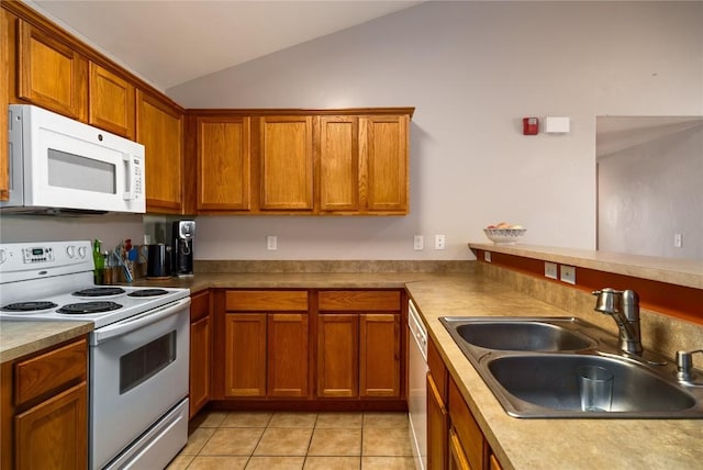 kitchen with white appliances, light tile patterned floors, brown cabinetry, lofted ceiling, and a sink