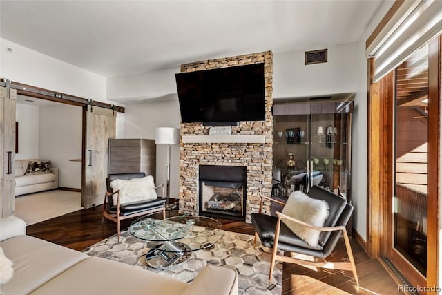 living room with a fireplace, hardwood / wood-style floors, and a barn door