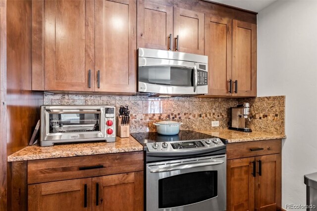 kitchen with tasteful backsplash, light stone counters, and stainless steel appliances