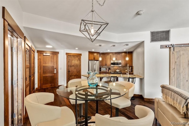 dining space featuring a barn door and dark hardwood / wood-style floors