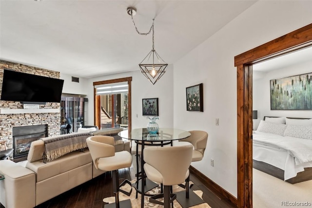 dining room with wood-type flooring and a stone fireplace