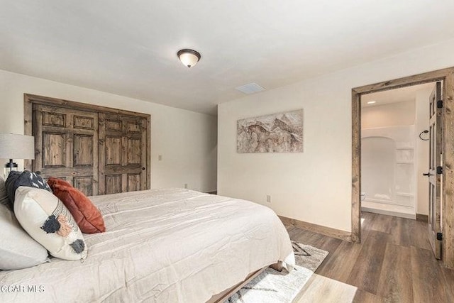 bedroom with dark hardwood / wood-style flooring and connected bathroom