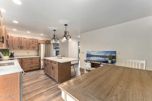 kitchen featuring a chandelier, stainless steel fridge, light hardwood / wood-style flooring, and hanging light fixtures