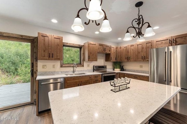 kitchen with light stone countertops, appliances with stainless steel finishes, sink, pendant lighting, and a notable chandelier