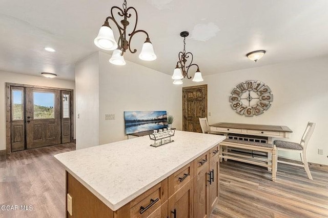 kitchen with decorative light fixtures, a kitchen island, dark hardwood / wood-style flooring, and a chandelier