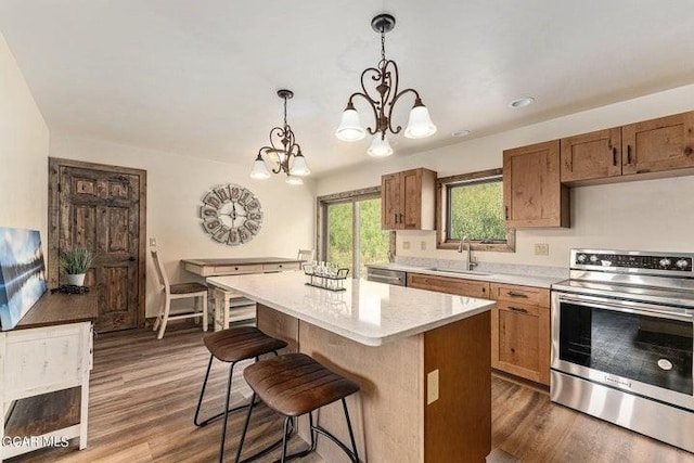 kitchen with pendant lighting, a center island, an inviting chandelier, sink, and appliances with stainless steel finishes