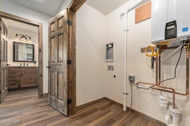 interior space with sink, dark wood-type flooring, electric dryer hookup, water heater, and hookup for a washing machine