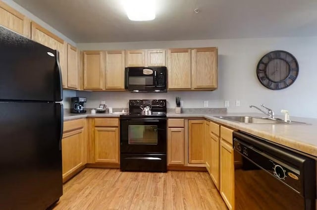 kitchen featuring a sink, light countertops, black appliances, light brown cabinetry, and light wood finished floors