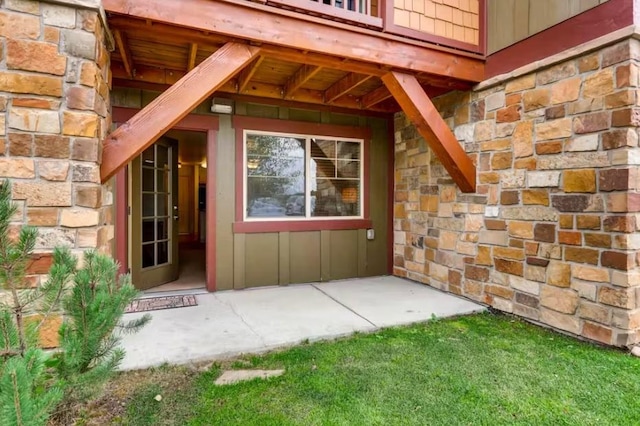 property entrance featuring stone siding, board and batten siding, and a patio area