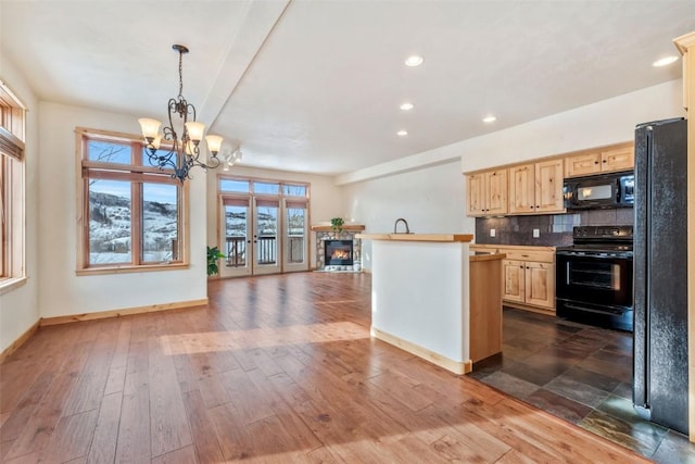 kitchen with a stone fireplace, dark hardwood / wood-style floors, light brown cabinetry, tasteful backsplash, and black appliances