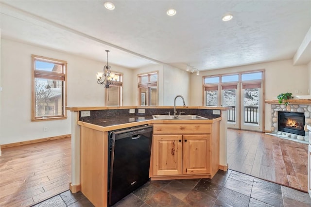 kitchen featuring a healthy amount of sunlight, decorative light fixtures, black dishwasher, and sink