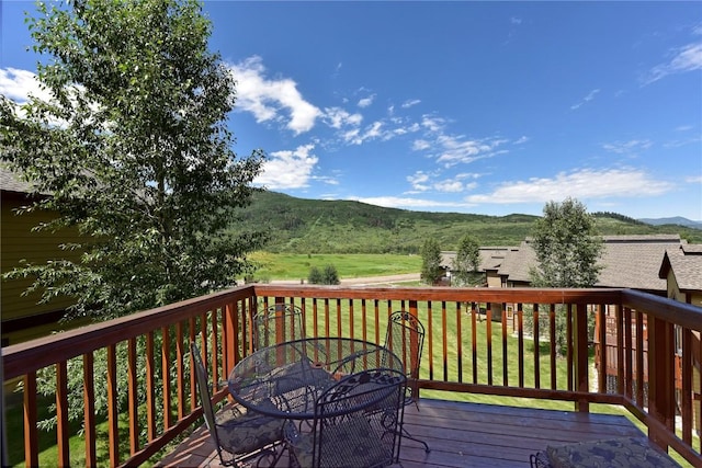 wooden deck with a yard and a mountain view