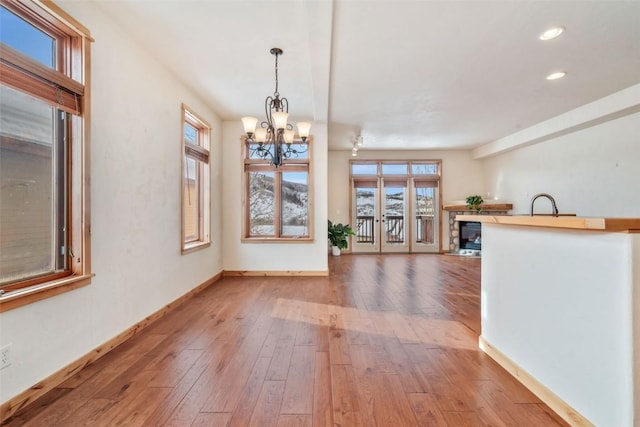 interior space featuring a notable chandelier, light hardwood / wood-style flooring, sink, and french doors