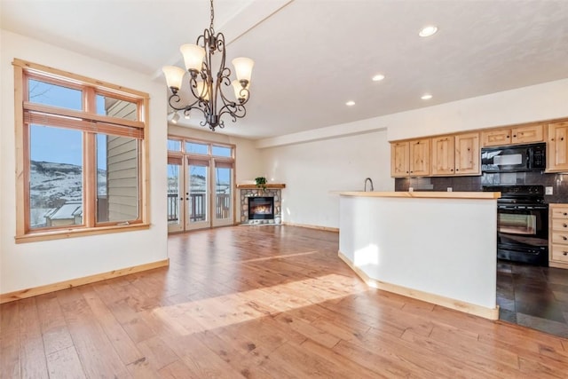 kitchen with a stone fireplace, pendant lighting, backsplash, black appliances, and light brown cabinets