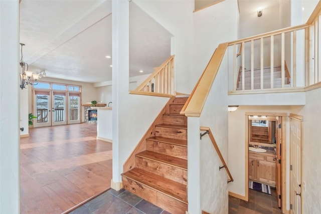 stairs featuring an inviting chandelier, sink, a fireplace, and wood-type flooring