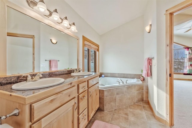 bathroom with a relaxing tiled tub, lofted ceiling, tile patterned flooring, and vanity