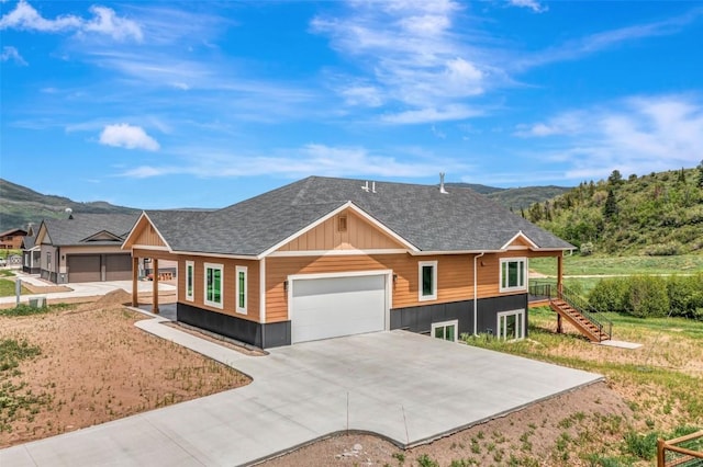 view of front of home with driveway, a shingled roof, an attached garage, stairs, and a mountain view