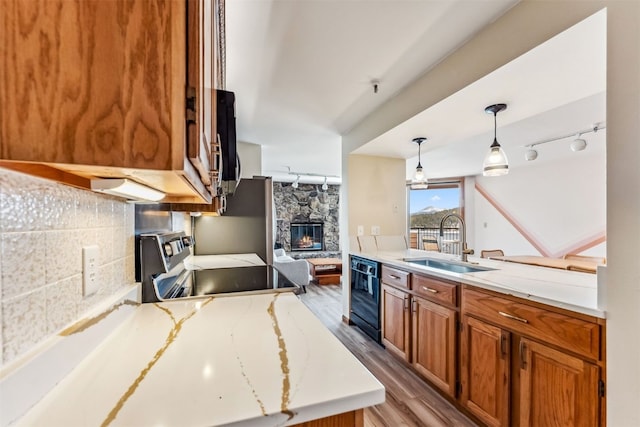 kitchen featuring sink, a stone fireplace, light hardwood / wood-style flooring, stove, and decorative light fixtures