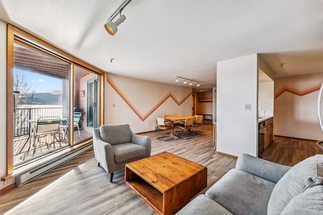 living room with light hardwood / wood-style floors, track lighting, and a baseboard heating unit