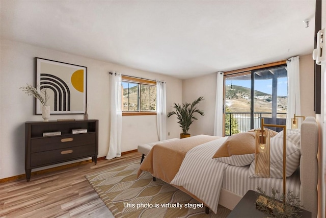 bedroom featuring a mountain view, light hardwood / wood-style floors, and access to outside