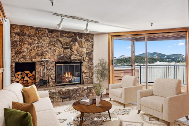 living room featuring a fireplace, a mountain view, and rail lighting