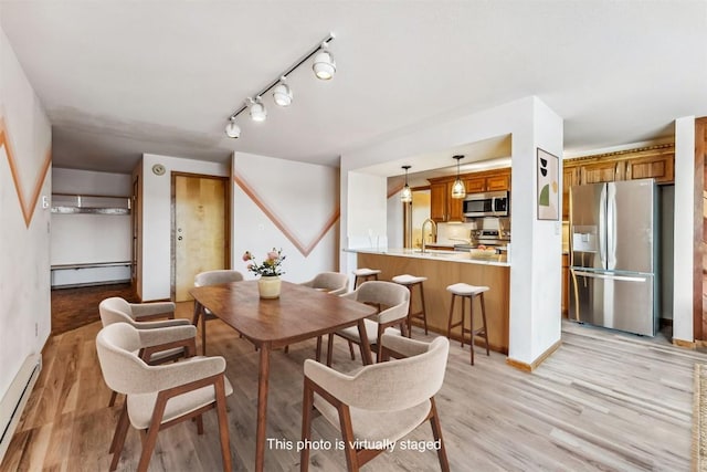 dining room featuring light hardwood / wood-style floors, sink, and baseboard heating