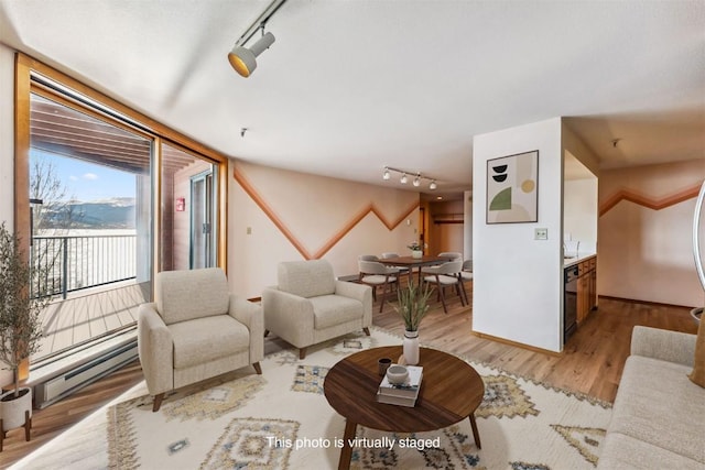 living room featuring light wood-type flooring, rail lighting, and a baseboard heating unit