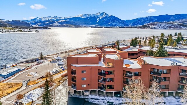 snowy aerial view with a water and mountain view