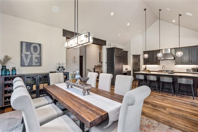 dining area featuring sink, high vaulted ceiling, and light hardwood / wood-style floors