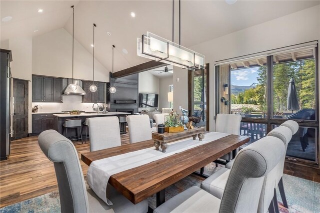 dining room with light hardwood / wood-style floors, high vaulted ceiling, ceiling fan, and sink