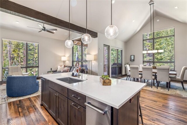 kitchen with dark brown cabinetry, dark wood-type flooring, sink, decorative light fixtures, and an island with sink