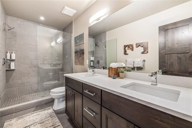 bathroom featuring tiled shower, tile patterned floors, vanity, and toilet