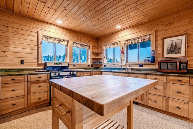 kitchen with butcher block countertops, gas stove, wooden ceiling, and a healthy amount of sunlight