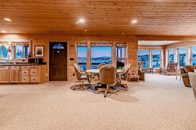 carpeted dining area featuring recessed lighting, wooden ceiling, and wooden walls