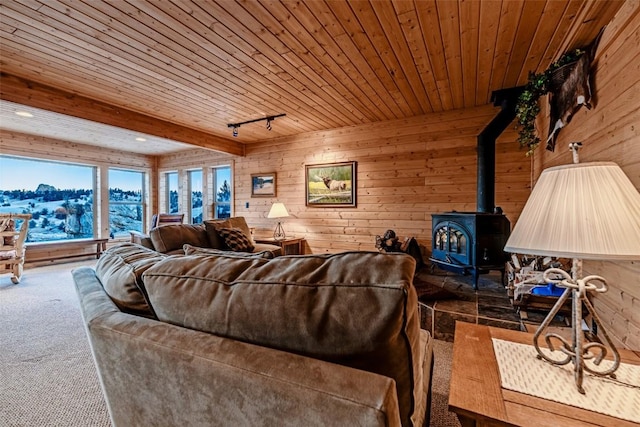 carpeted living room featuring beamed ceiling, wooden ceiling, a wood stove, and wooden walls