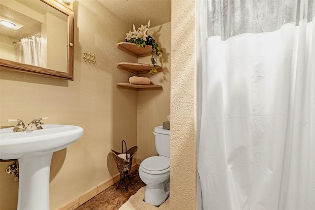 full bathroom with toilet, a shower with curtain, baseboards, and a sink