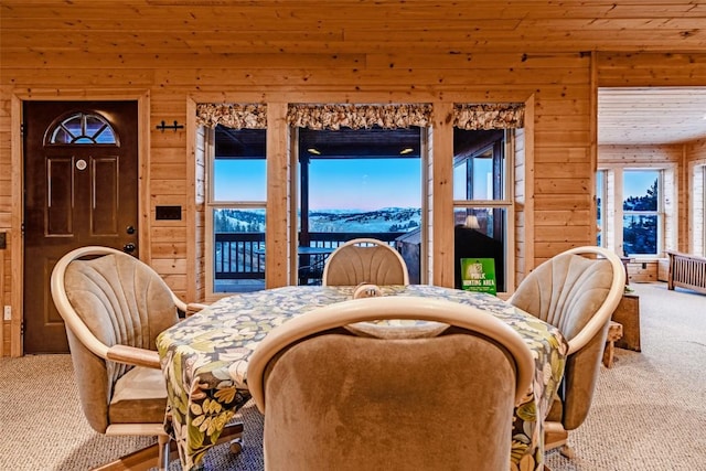 dining space featuring carpet and wooden walls