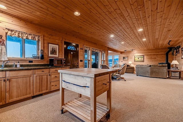 kitchen with wooden ceiling, light carpet, wood walls, a sink, and wooden counters