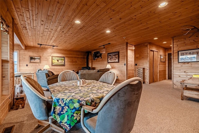 carpeted dining space with visible vents, wood ceiling, a wood stove, rail lighting, and recessed lighting