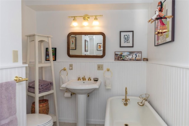 bathroom featuring toilet and a tub to relax in