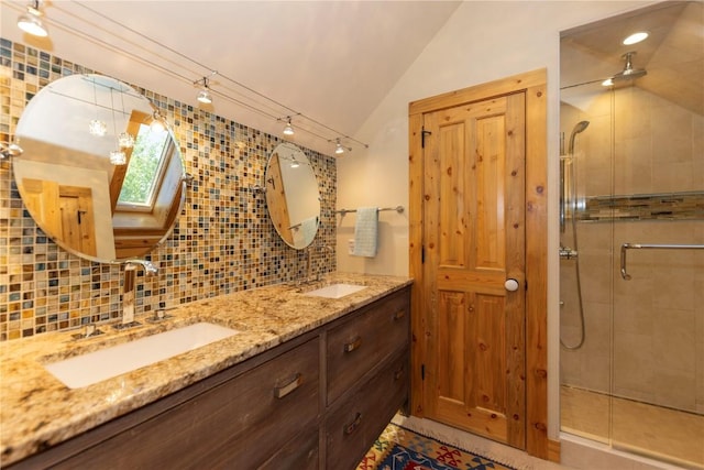 bathroom featuring vaulted ceiling with skylight, vanity, a shower with shower door, and tasteful backsplash