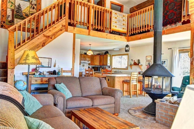 living room with carpet, a wood stove, and a high ceiling