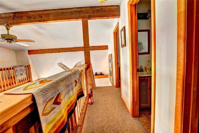 hallway with carpet flooring and beam ceiling