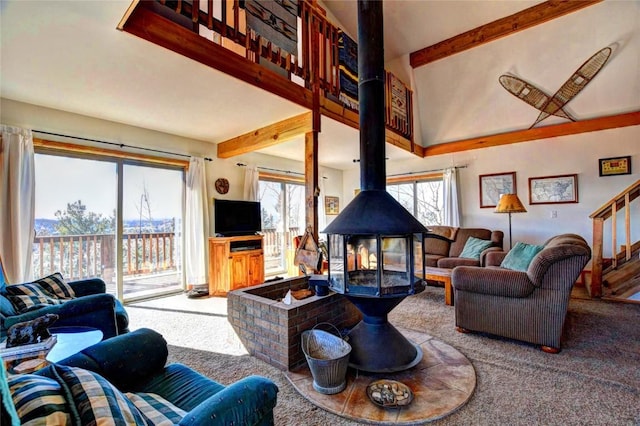 living room featuring carpet, beam ceiling, a wood stove, and a high ceiling