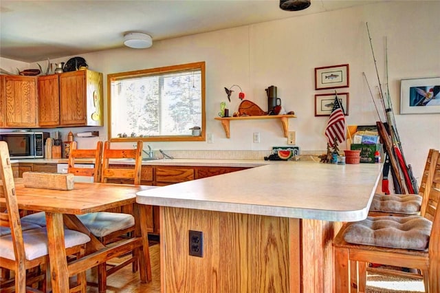 kitchen with a kitchen bar, kitchen peninsula, sink, and light parquet floors